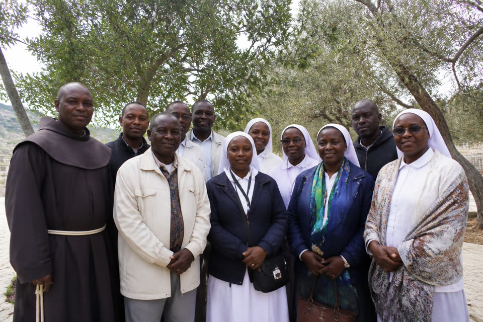 Kisumu Olive Path pilgrims standing together beneath olive trees